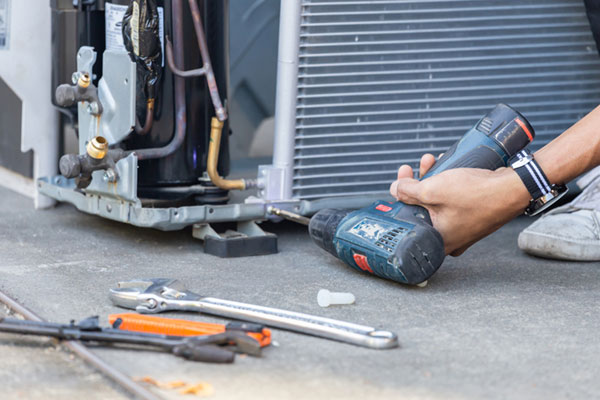 Selective focus Air Conditioning Repair, technician man hands using a screwdriver fixing modern air conditioning system.