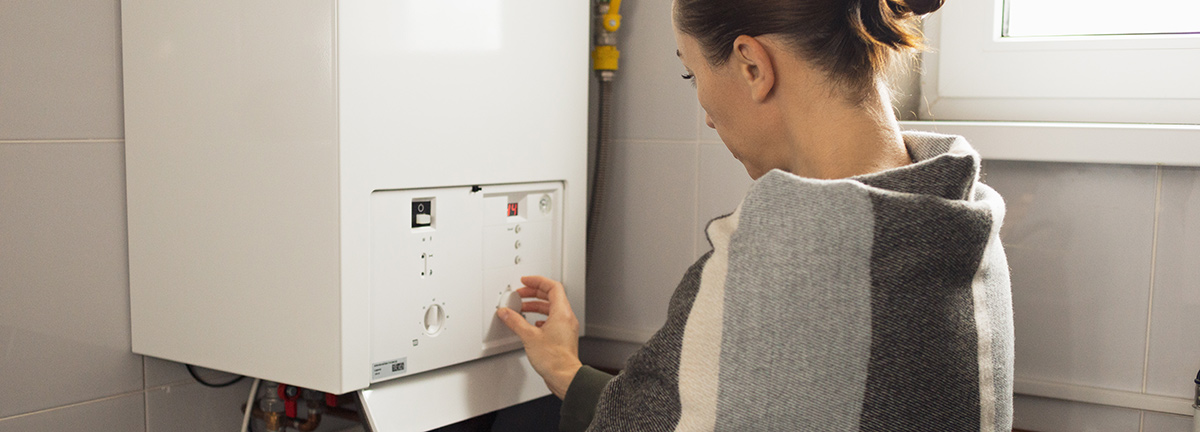 a tankless water heater being looked at by a woman in a sunny basement.